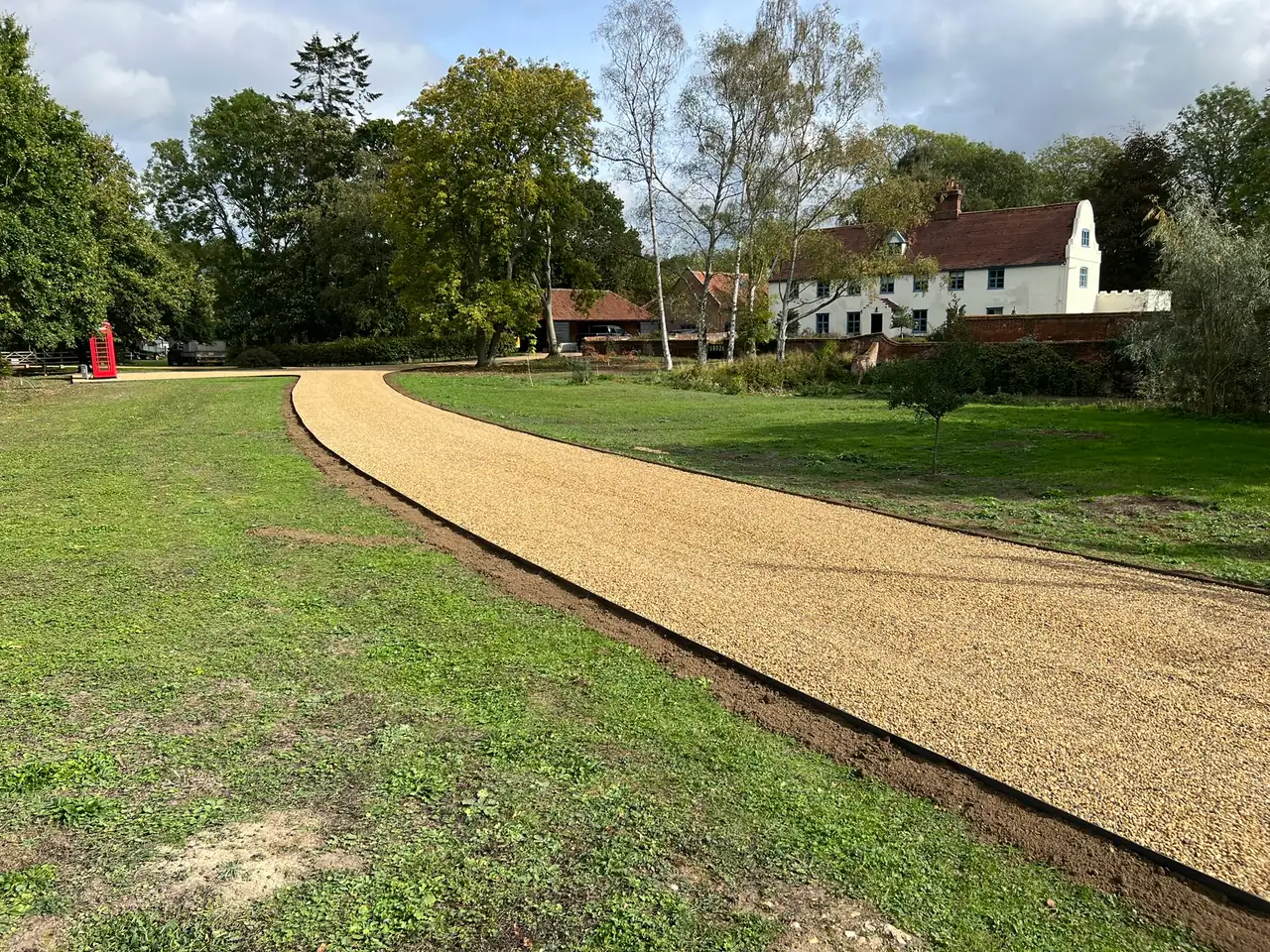 Tar and chip driveway sweeping up to a Norfolk hall, surrounded by trees in autumn
